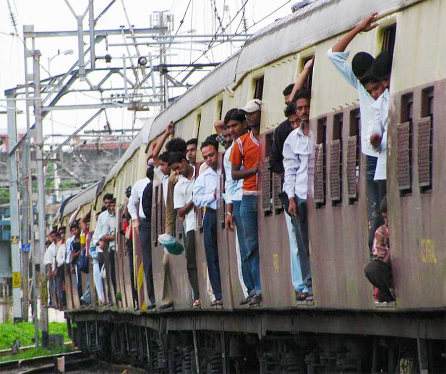 Les passagers voyagent sur le côté d'un train de banlieue à Mumbai